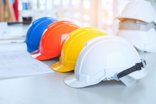 Red Yellow White and blue Safety hard hat on the blueprint with Red Yellow White and blue Safety hard hat on the blueprint with